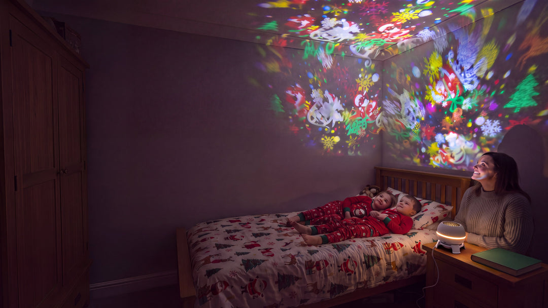 Le soir, une maman et ses enfants regardent les dessins de Noël au plafond de la chambre