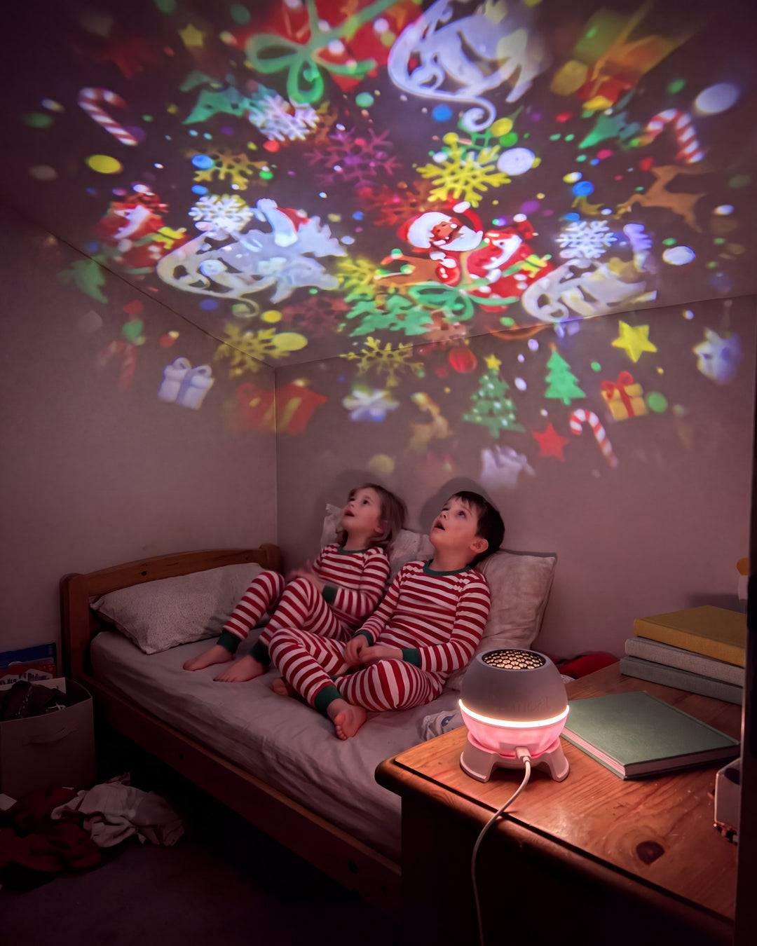 Deux enfants en pyjama regardent les dessins de Noël au plafond de leur chambre