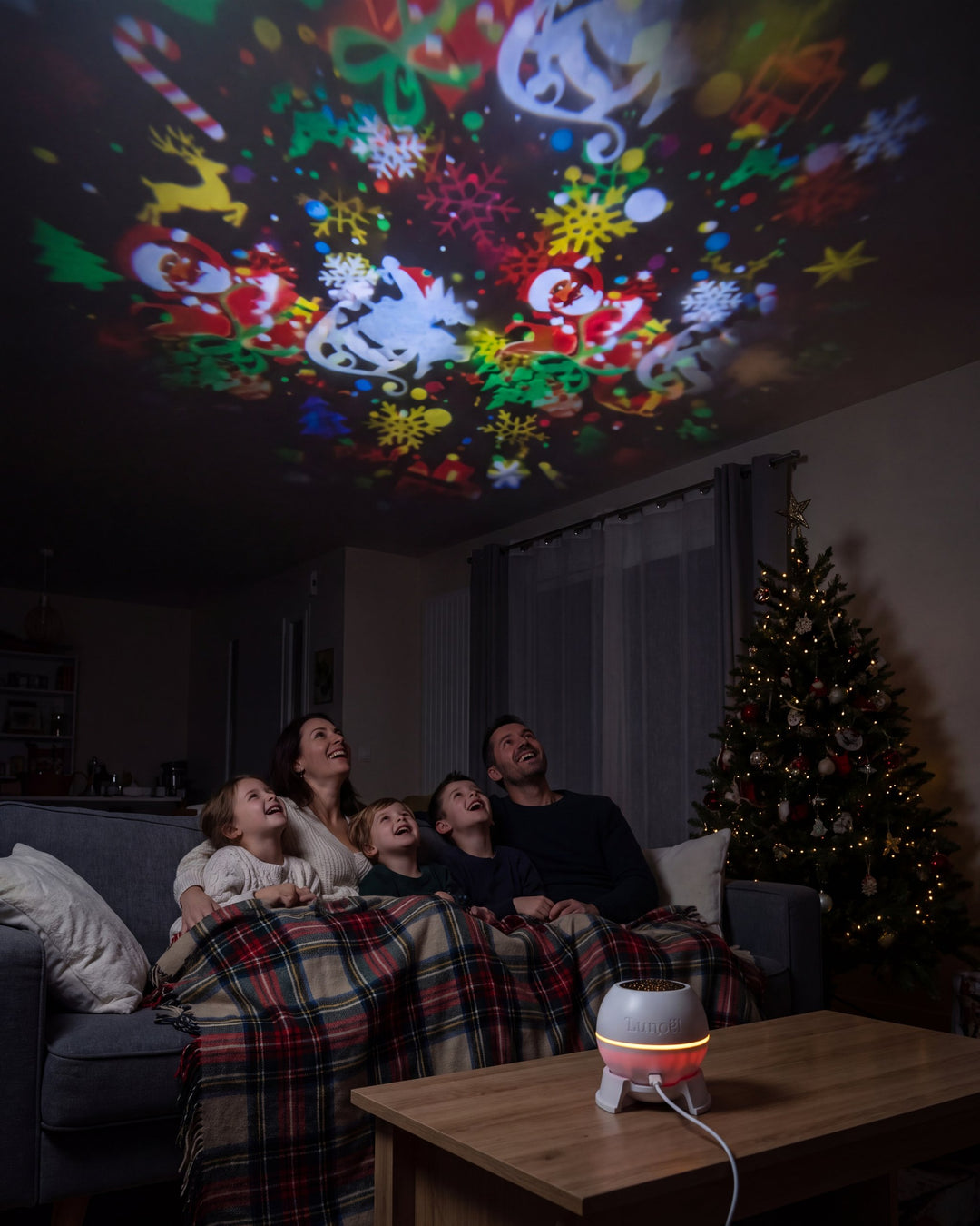 Une famille sur le canapé regarde les dessins de Noël au plafond du salon