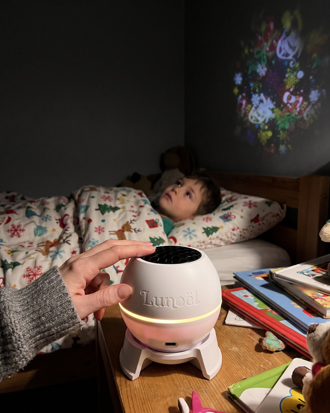 Une main allume la sphère Lunoël sur la table de nuit, l'enfant est sous la couette